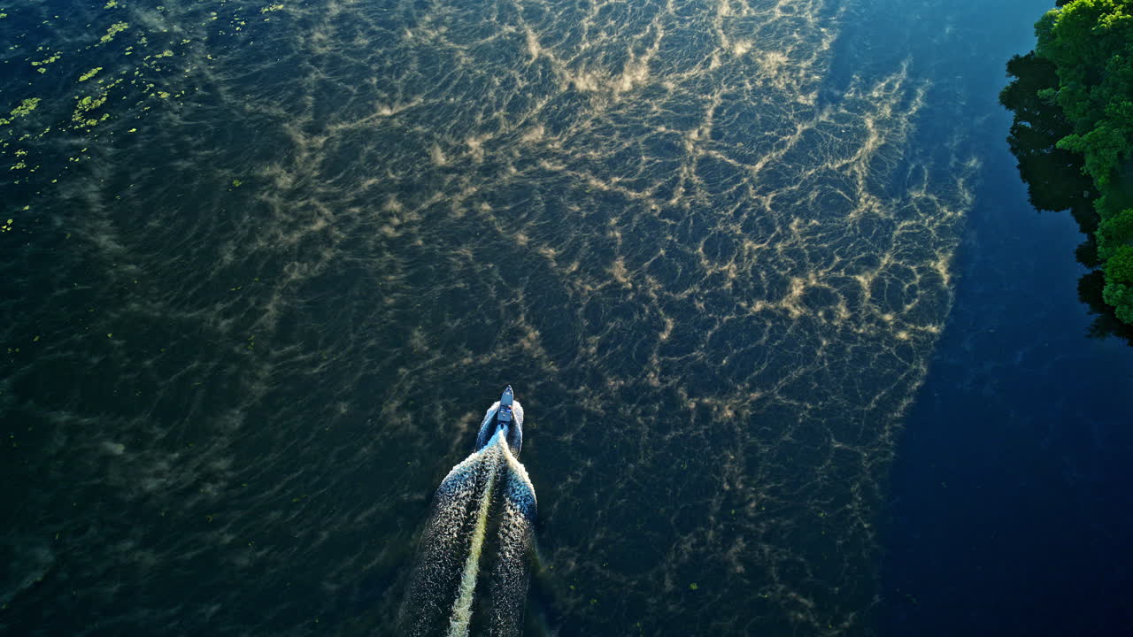 Slow motion drone footage for motorboat cruising up a foggy river at sunrsie