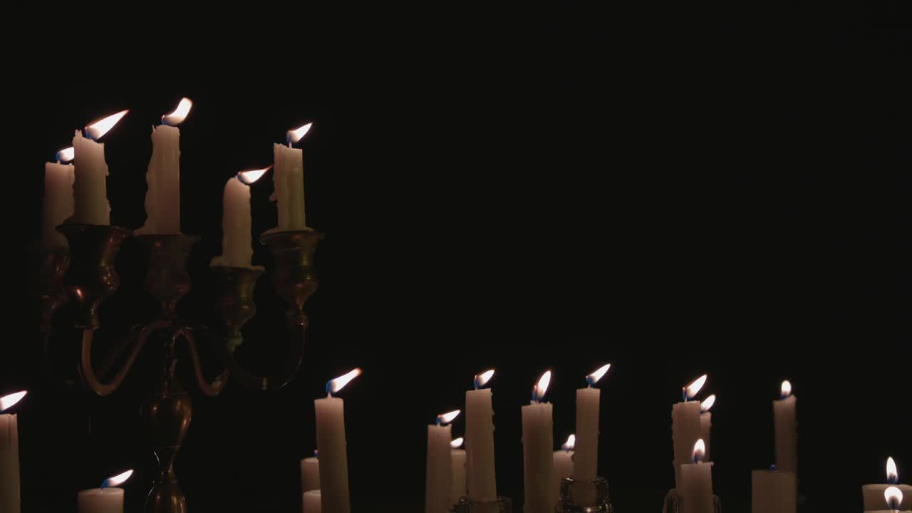 un grupo de velas blancas, algunas en un candelabro, encendidas y funcionando durante un tiempo