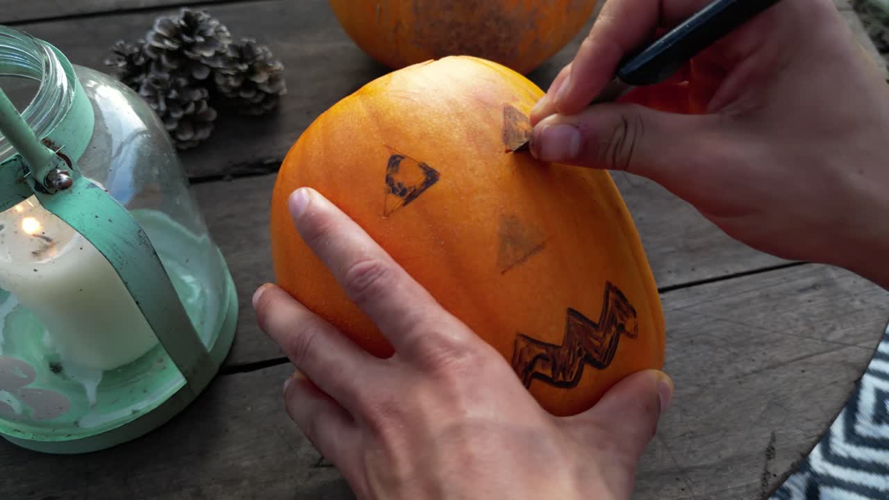 primer plano de la mano masculina tallando los ojos de jack-o-lantern para halloween