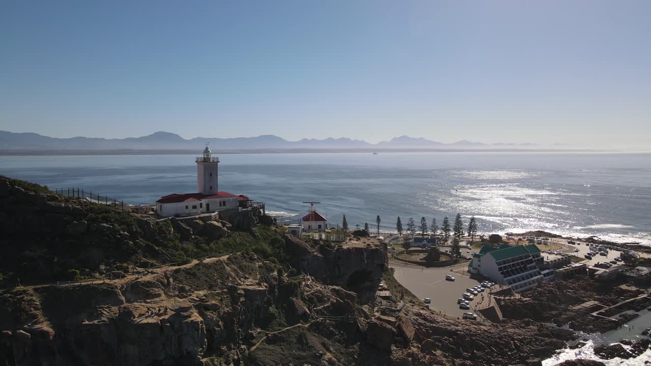 화창한 날 바다를 배경으로 등대를 향해 산 절벽 위로 날아가는 드론 샷