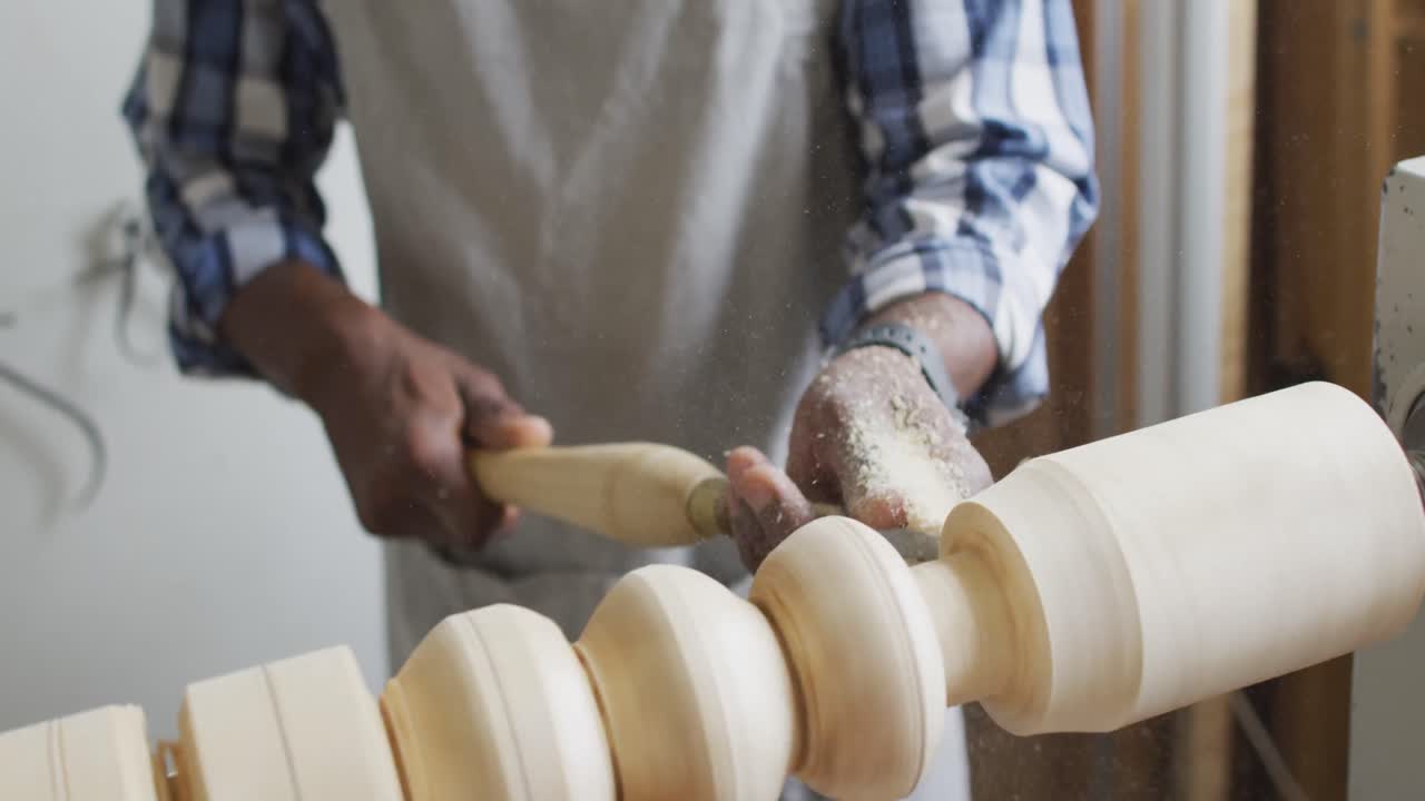 carpintero afroamericano de sexo masculino con casco protector girando madera en un torno en una carpintería