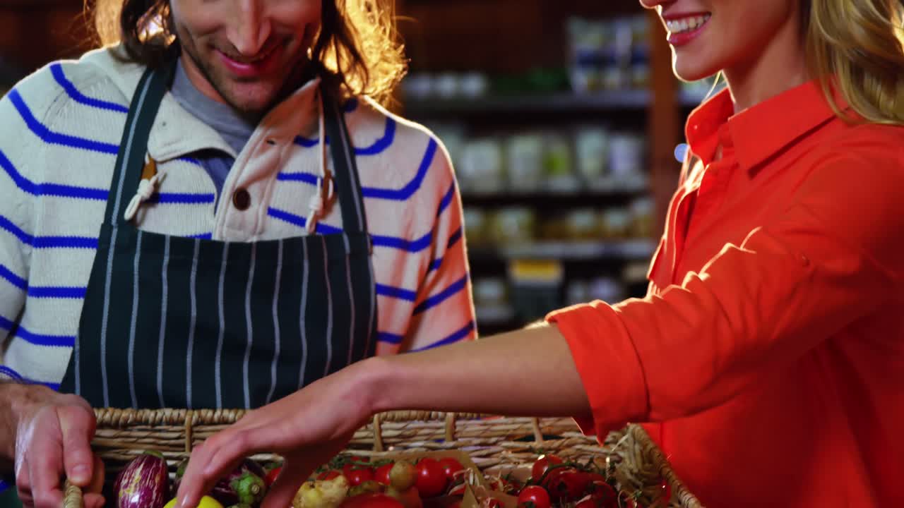 personal masculino ayudando a la mujer a seleccionar verduras frescas