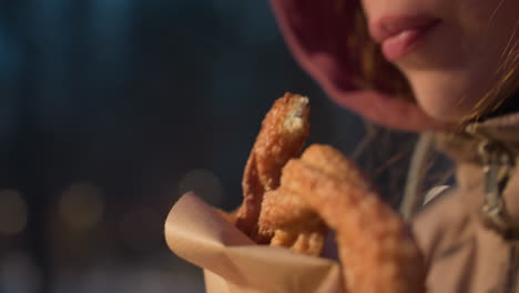 close-up of woman biting crispy snack, with warm light reflecting off face, capturing moments of indulgence and satisfaction, snack in hand with golden crispy