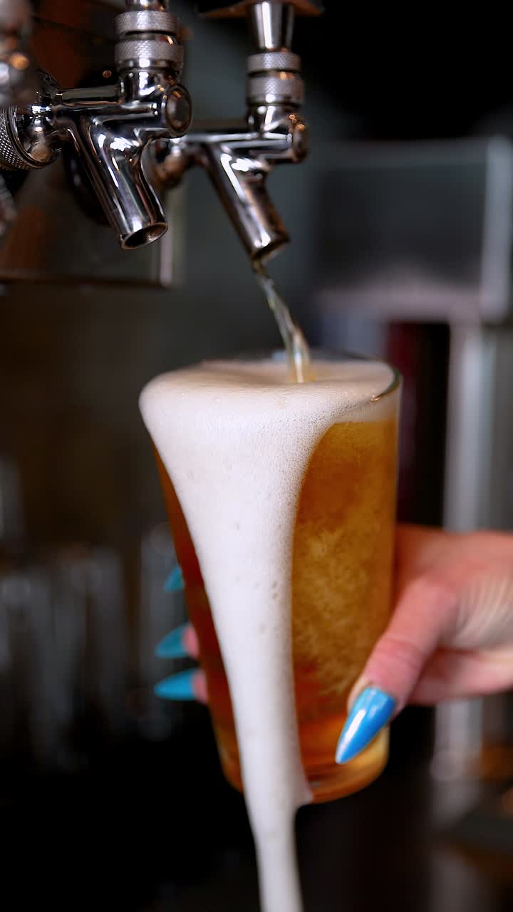 Bartender tilts a glass under the tap as foamy beer pours in a smooth controlled motion, vertical