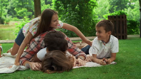 Familia-Acostada-Sobre-Una-Manta-En-El-Parque.-Padres-Divirtiéndose-Con-Niños-En-El-Bosque