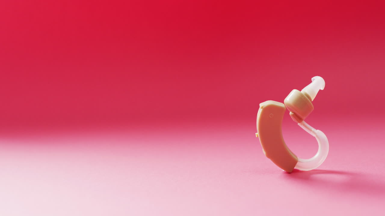 video de un audífono en fondo rojo con espacio para copiar.