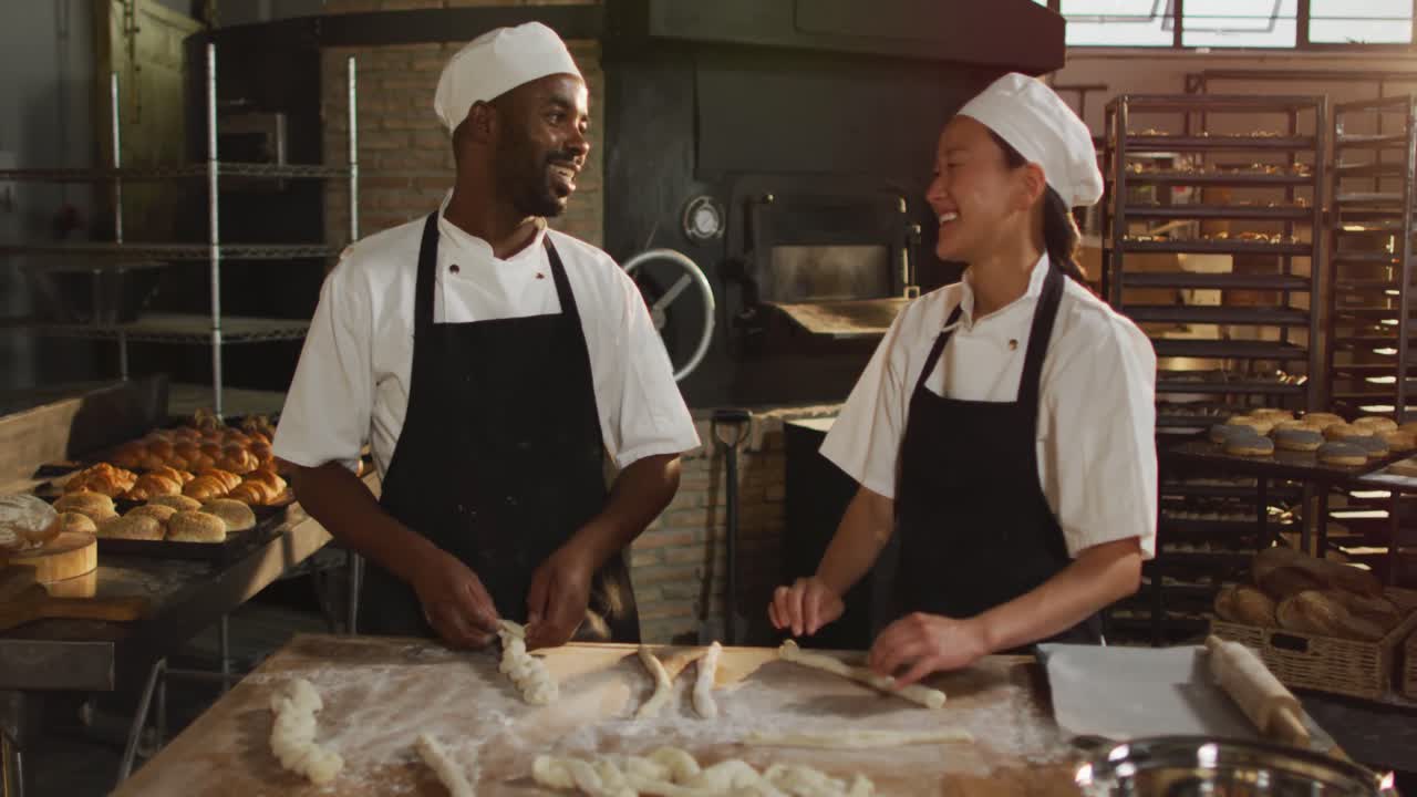 Animation of happy diverse female and male bakers preparing rolls at bakery