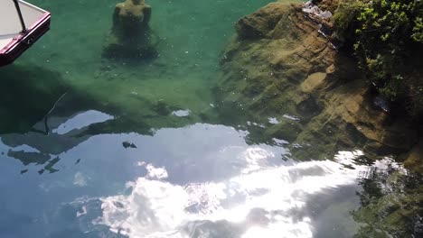 Female-maiden-statue-sunken-in-crytal-clear-turquoise-water-of-blausee-alpine-lake-in-swiss-alps-of-Kandersteg,-Switzerland