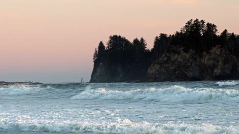 stunning slow motion shot of the beautiful ruby beach near forks, washington during golden hour with a small cliff island and waves crashing into the shore