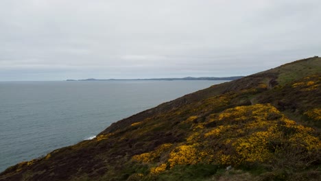 Antena-De-Drones-Ascendente-Con-Camino-Costero-Mar-Tranquilo-Con-Pembrokeshire-En-La-Distancia-Reino-Unido-4k