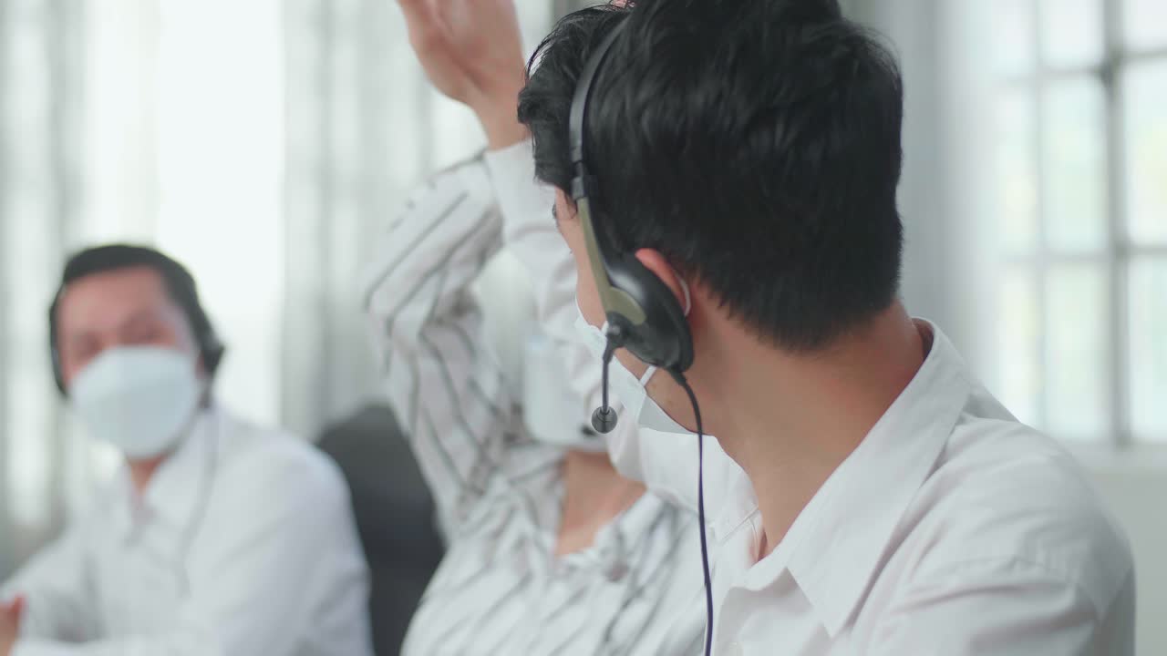 Close Up Of Three Asian Call Center Agents Wearing Headsets And Masks Being Happy Due To Success Working At The Office
