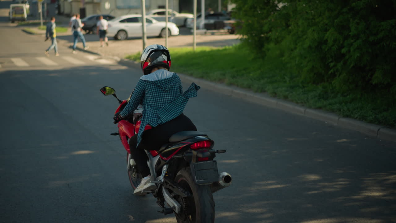 은 전력 자전거를 타고 평온한 도시 도로를 가로질러 이동하는 라이더, 라이더는 색 셔츠와 헬을 입고 멀리서 보행자들과 함께 보행자 교차로를 향하고 있습니다.