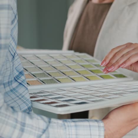 woman chooses the color of his order by the catalog which is held by the manager