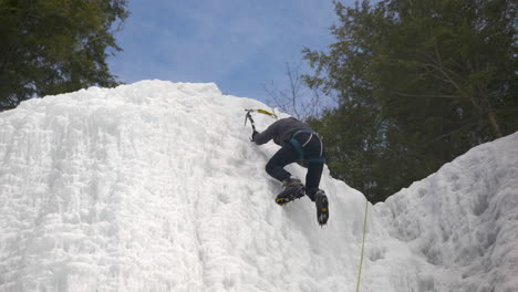 a climber reaches the summit of a frozen cliff face