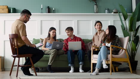 Grupo-De-Estudio-Sentado-En-Un-Sofá-Y-Sillas-Mirando-Portátiles-Y-Portátiles