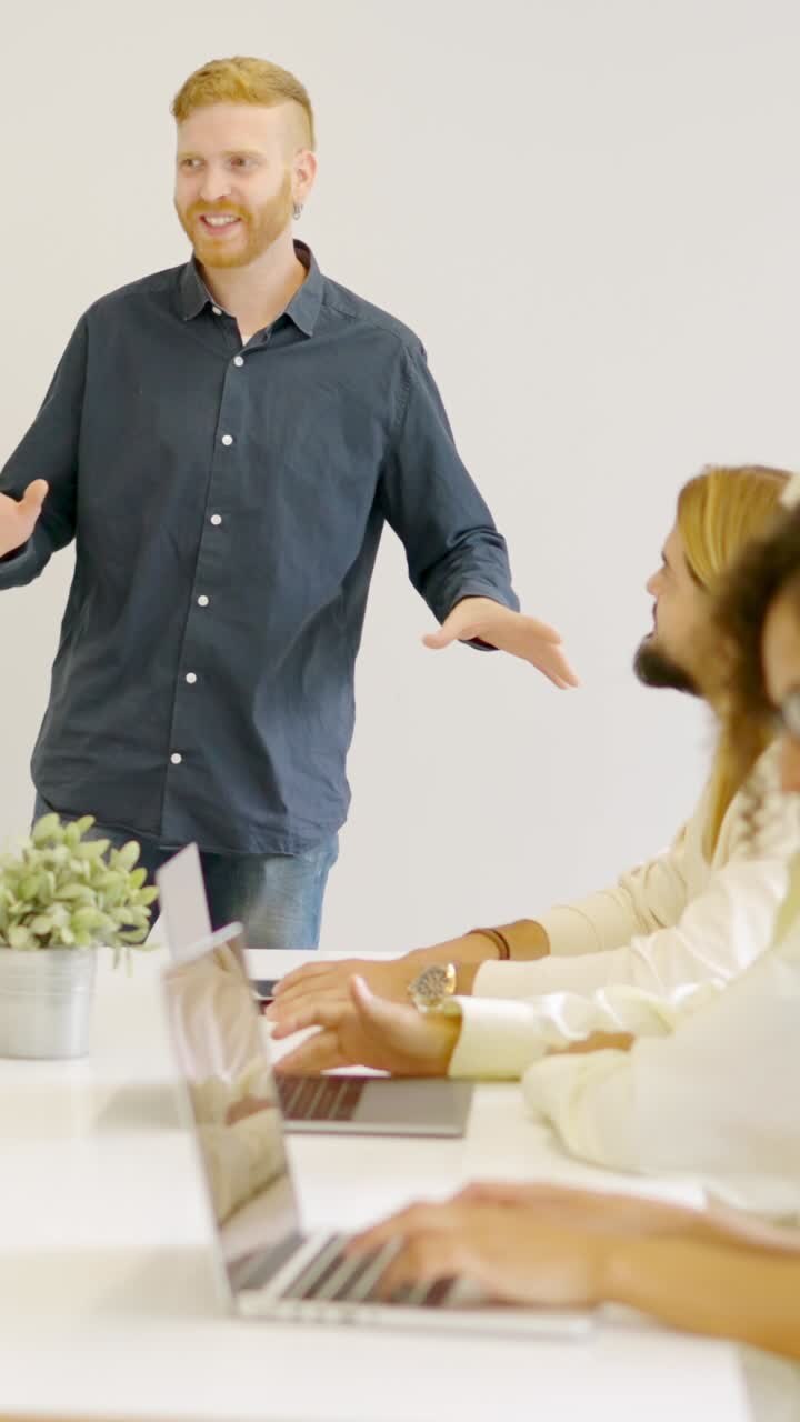 Man leading a meeting in a coworking using a board