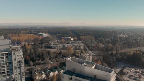 Drone-4K-Footage-Above-Surrey-cityscape-with-highrise-buildings-train-track-roads-and-parking-lots-with-traffic-congestion-and-pollution
