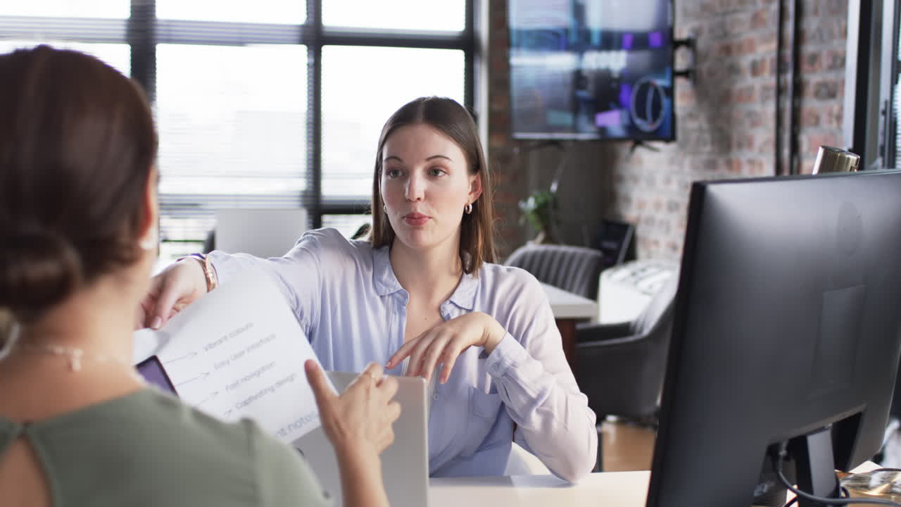 una joven caucásica está discutiendo un documento de negocios con un colega asiático.