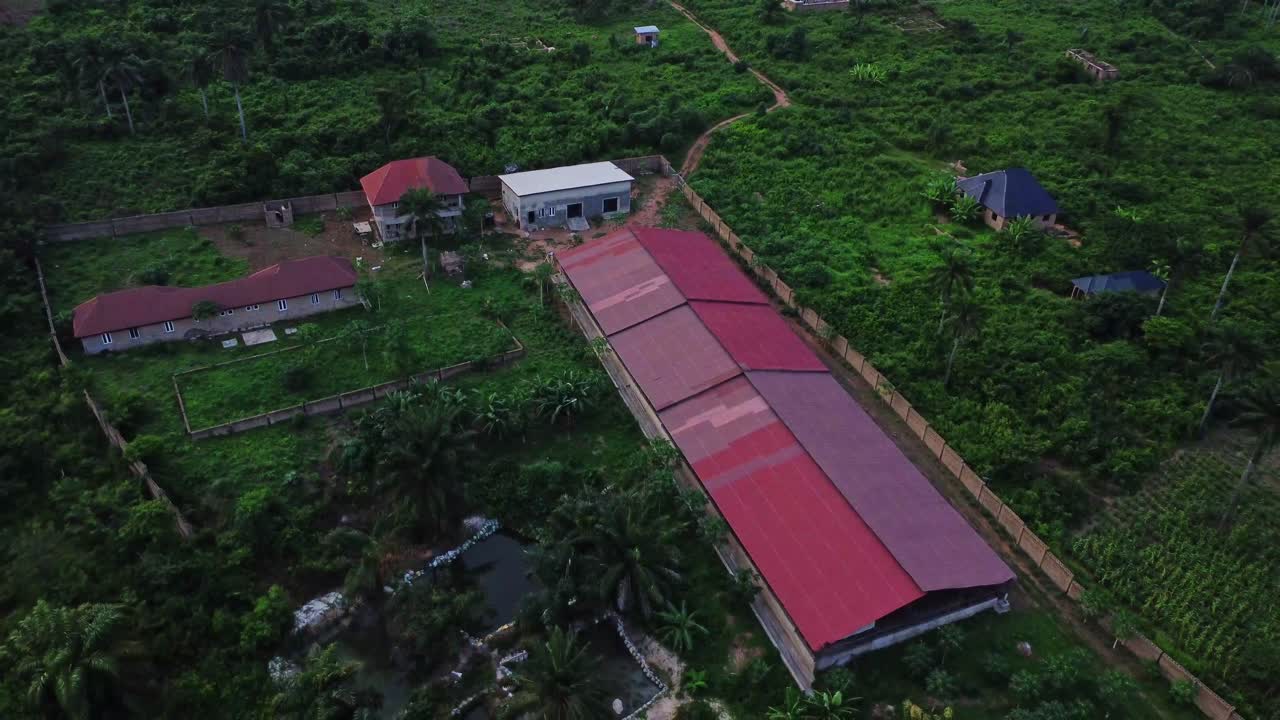 Beautiful aerial of a large farm of poultry, fish ponds and pigs surrounded by lush plots of land and green forests in the countryside of Nigeria, Africa. A beautiful farm of chicken and livestocks