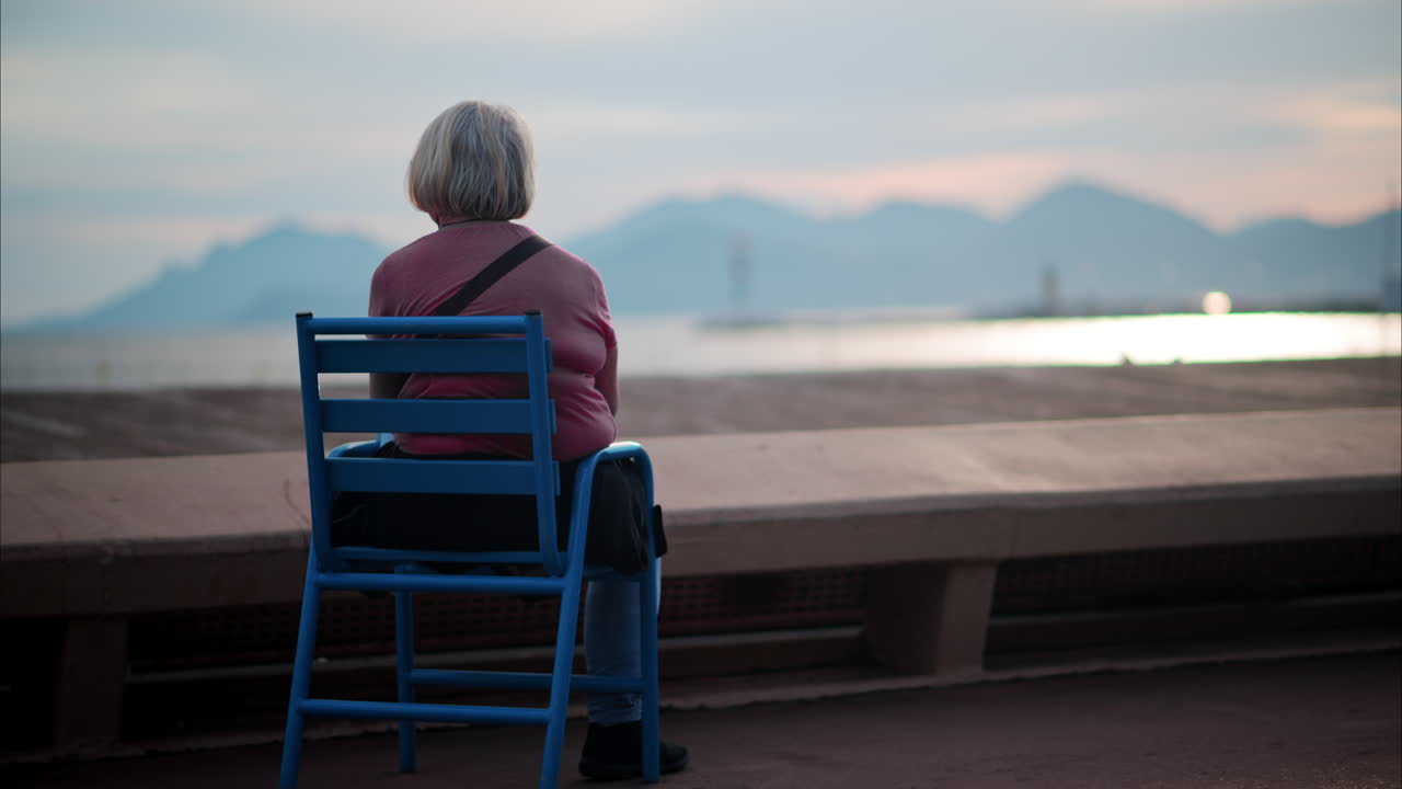 Old woman sitting on a chair at the beach in France