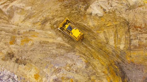 aerial view of bulldozer working on muddy construction site or open cast mine. heavy industry from above.