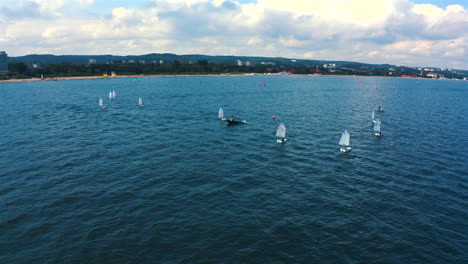 Optimist-dinghy-sailing-on-the-blue-waters-of-Baltic-sea-near-seashore-at-sunny-vacation-day