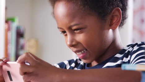 Niño-Sentado-En-El-Escritorio-En-El-Dormitorio-Jugando-En-El-Teléfono-Móvil