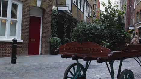 covent garden classic wood plant horse cart. people passing by wood horse cart near the red door and vintage house. decorate design covent garden classic wood plant horse cart. london, united kindom