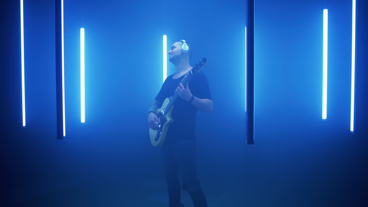 블루 램프의 원에서 기타를 연주하는 남성 록 연주자