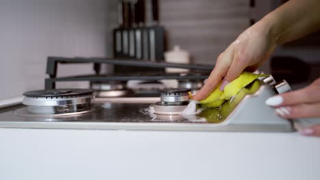 hand cleaning stove. close up of female hand cleaning the gas stove in kitchen