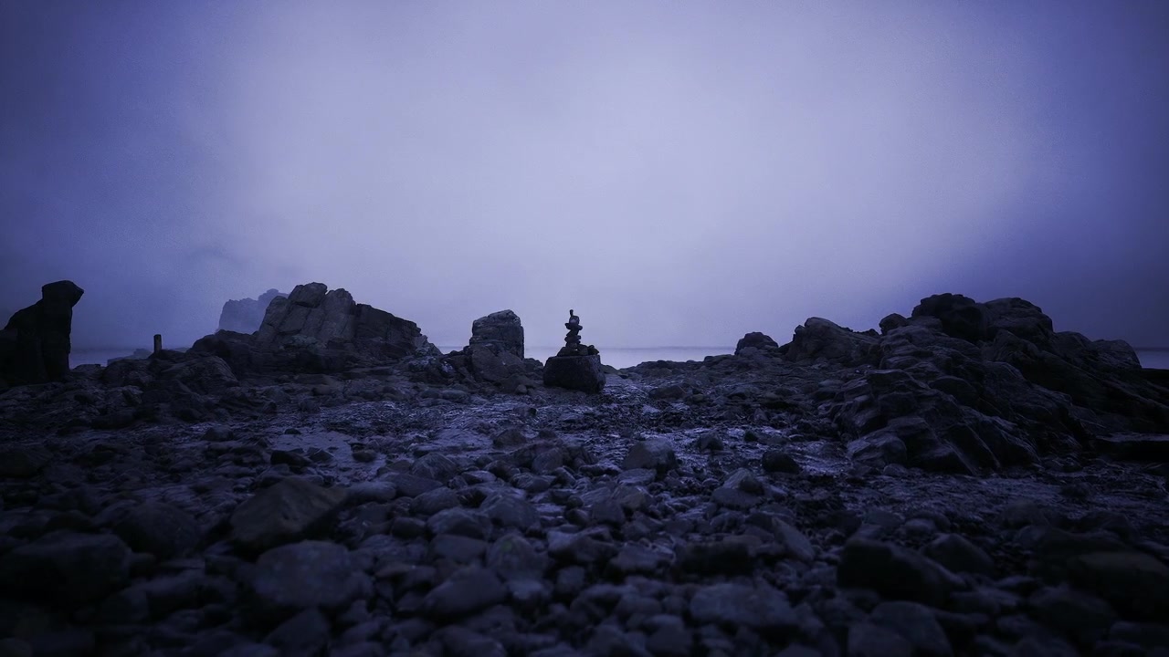 Tranquil pebbled beach featuring cairns and misty distant view