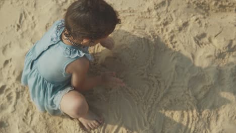 top down view of young toddler playing in sand at beach with sun rays behind