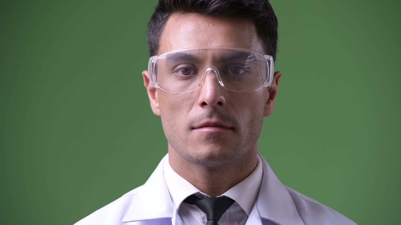 Giovane e affascinante medico ispanico su sfondo verde.