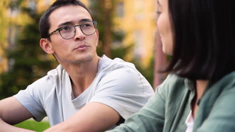 joven japonés hablando con su amiga mientras se sientan juntos al aire libre