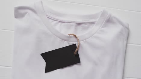 video of flat lay of white t shirt with tag and copy space on white background