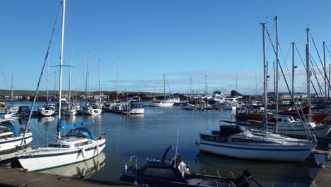 Drone-flying-through-marina-with-boats-and-yachts-moored-to-dock