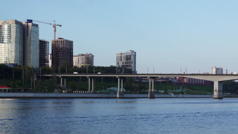 city river view with bridge, modern buildings, and construction crane