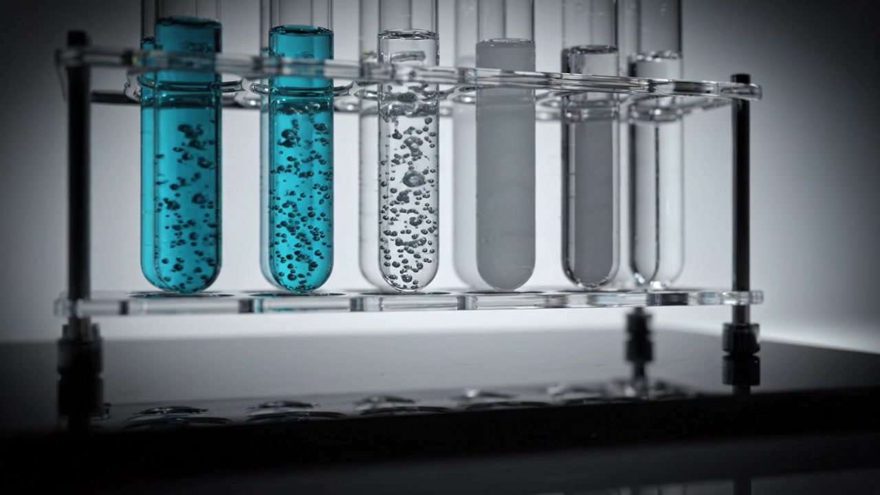 Test Tubes Containing Vibrant Blue and Clear Liquid with Bubbles on a Reflective Surface, Depicting an Experiment or Scientific Observation.
