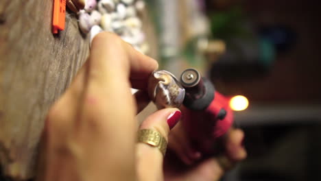 craftsman shaping sea shell to make jewelry, close up vertical video