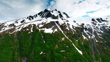snowy alaskan mountain view. stunning view of a snow-capped mountain in alaska surrounded by lush green valleys and cascading waterfalls