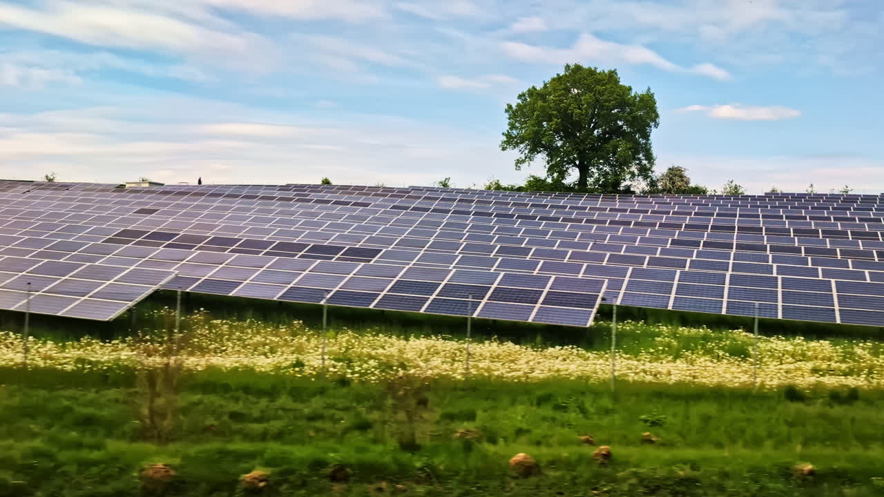 A large solar farm stretches across a grassy field, viewed from a moving train in Germany