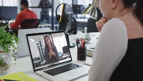 Caucasian-woman-having-a-video-call-on-laptop-with-female-colleague-at-office