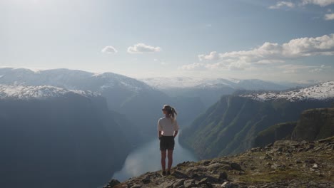 un excursionista se encuentra en el monte prest en noruega, con vistas a los impresionantes fiordos y picos nevados