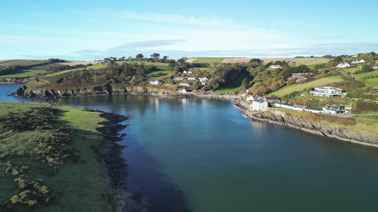 Long aerial coastal stretch Sandycove Kinsale, sheltered bay with cliffs and village in Ireland