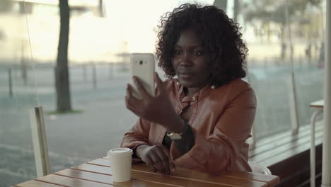 Woman-sitting-in-cafe-and-answering-video-call