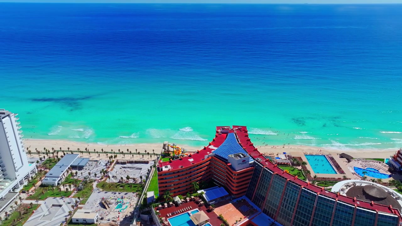 Vista aerea del tetto e della piscina di un resort che si affacciano sul Mar dei Caraibi turchese nella Zona Hotelera di Cancun, Quintana Roo, Messico.
