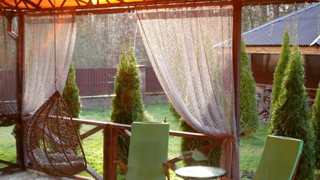 swing a cocoon, chair, table and curtains in the yard.