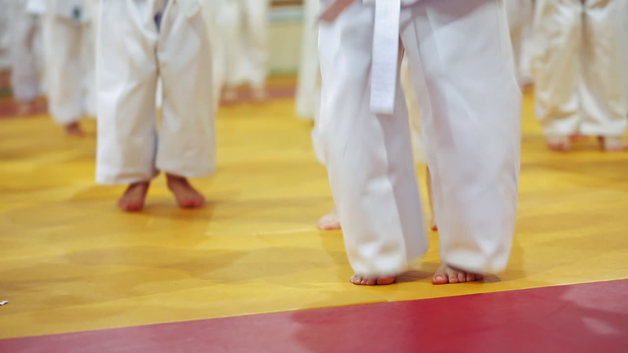 Children during training exercises. Close up of children in kimono jumping on tatami on martial arts