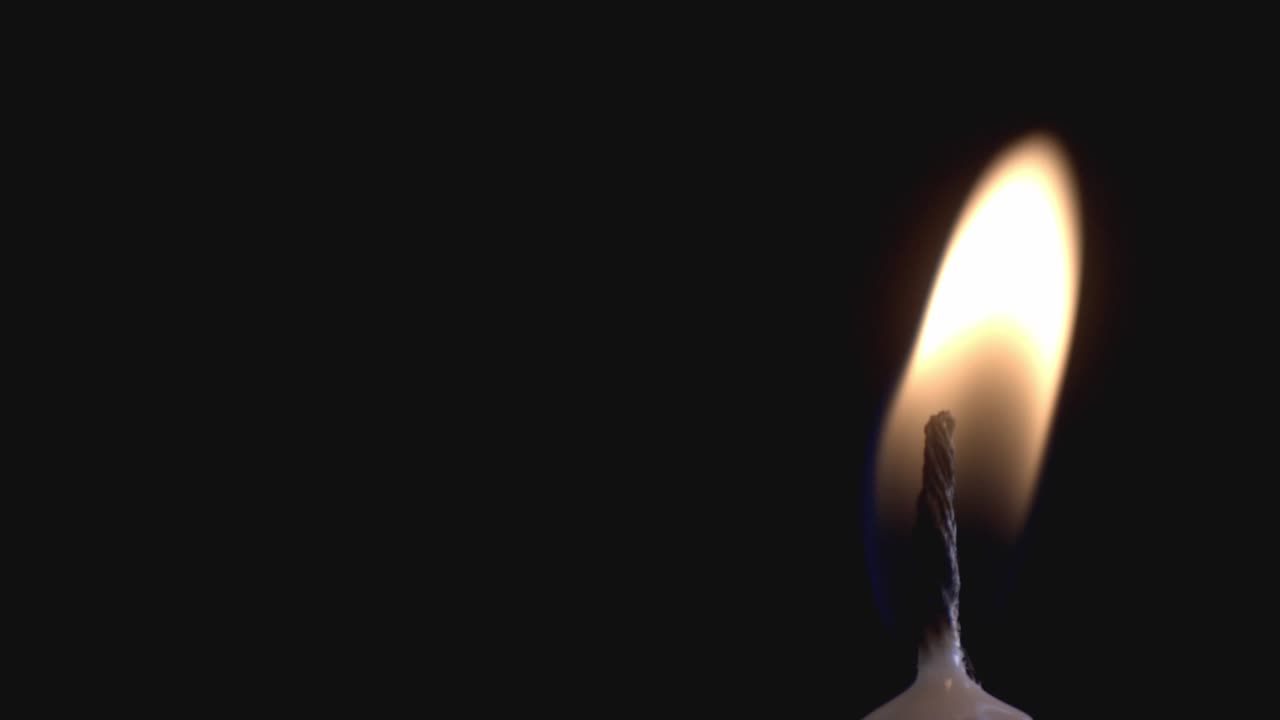 Candela illuminata dal vento su sfondo nero - primo piano