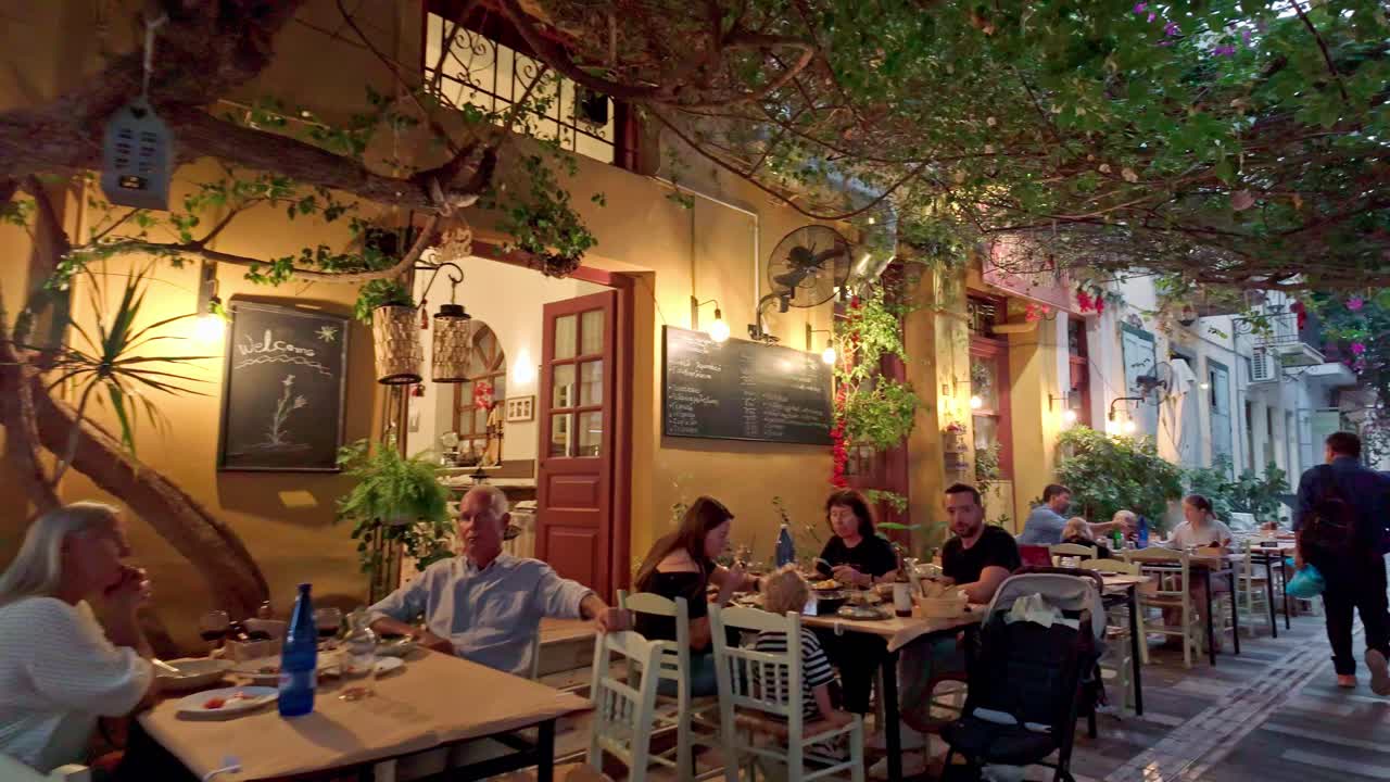 Greek narrow streets people dining al fresco cosy restaurants hand held walking shot